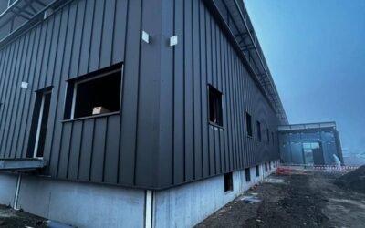 Angle bâtiment avec bardage métallique vertical et structure acier en toiture sur chantier carrefour vizille