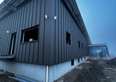 Angle bâtiment avec bardage métallique vertical et structure acier en toiture sur chantier carrefour vizille