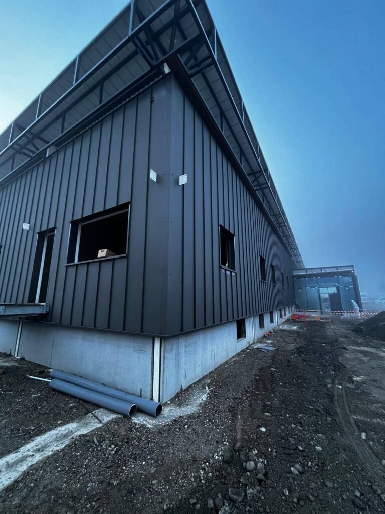 Angle bâtiment avec bardage métallique vertical et structure acier en toiture sur chantier carrefour vizille