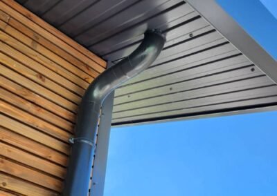 Détail finition toiture bac acier avec descente d’eau et habillage sous-face sur bâtiment technique à morzine