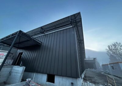 Façade bardage métallique vertical anthracite sur bâtiment erp en rénovation à vizille avec débord de toiture acier