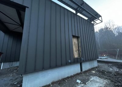 Pose de bardage acier vertical sur bâtiment industriel avec ouvertures en attente et soubassement béton