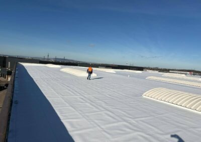 Technicien hordeau inspectant une toiture industrielle rénovée en membrane tpo réfléchissante